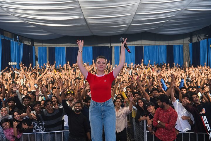 Performer with arms raised facing a cheering crowd